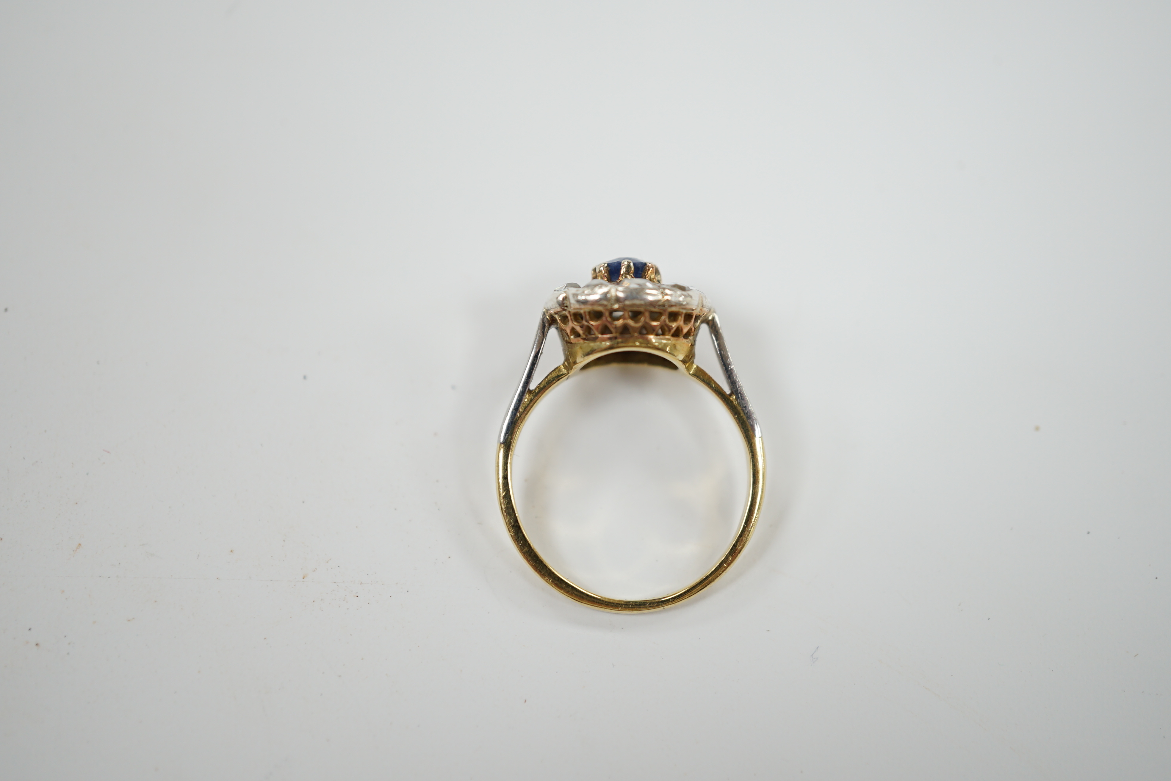 An early 20th century 18ct, single stone sapphire and ten stone rose cut diamond set circular cluster ring, size L, gross weight 3.9 grams.